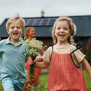 Two young children in garden of a house featuring prominent solar panels